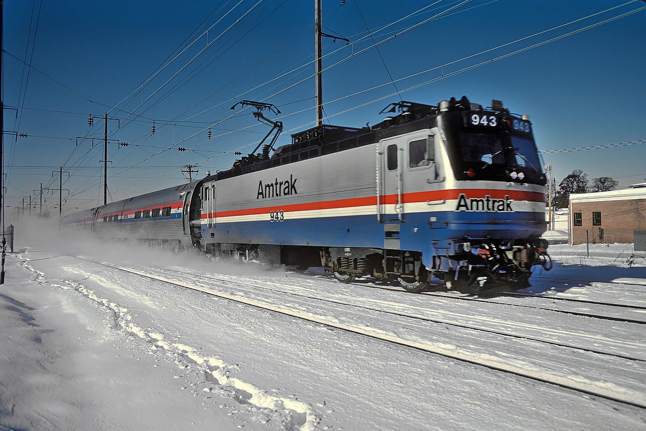 Electric Amtrack train driving down the snowy landscape