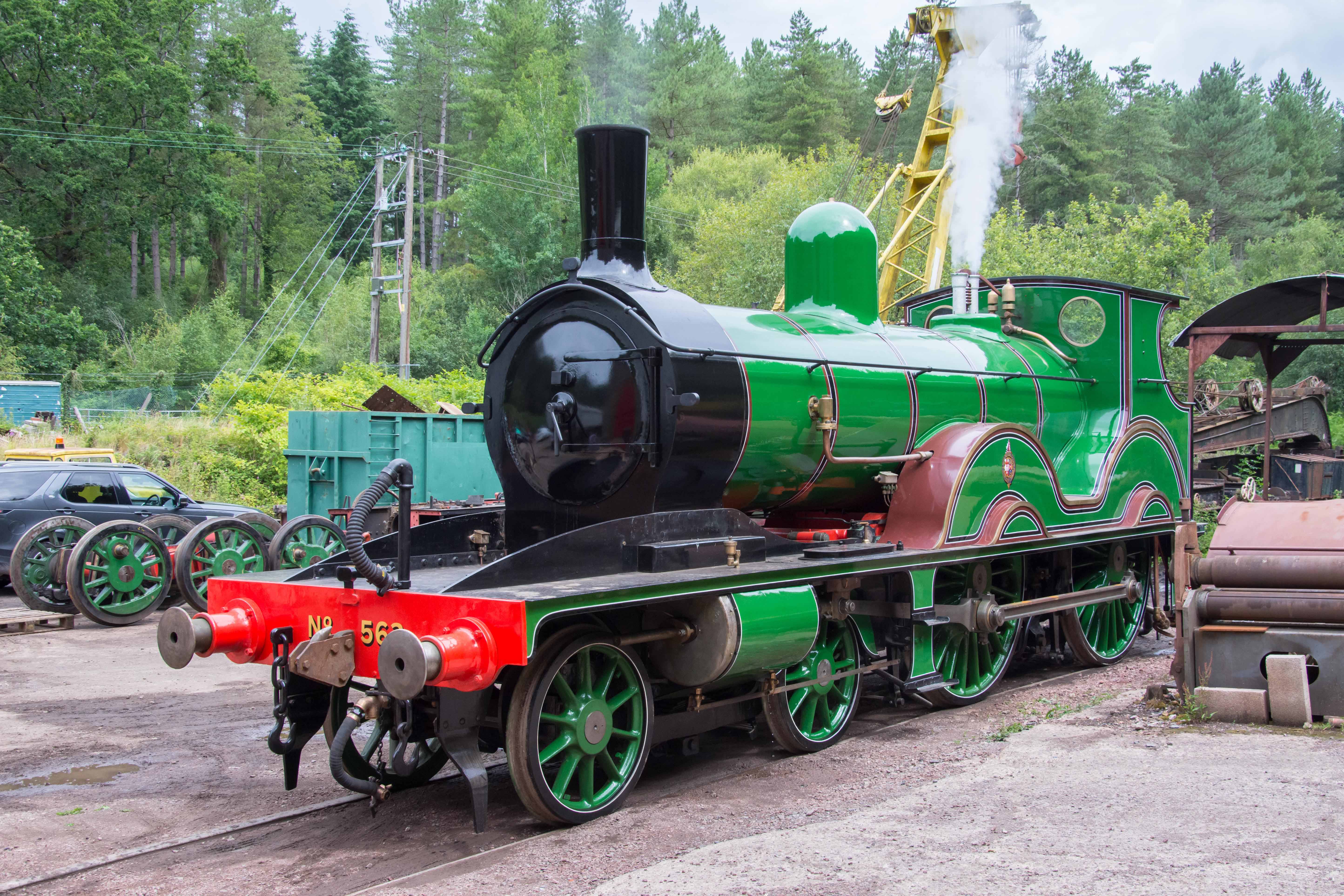 Shiny green steam engine at a scrap yard.